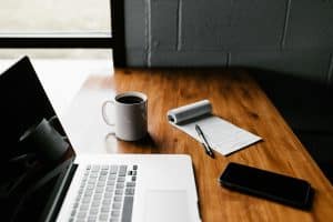 Rédaction sur ordinateur portable avec carnet et café